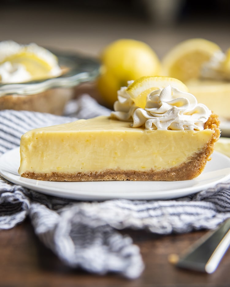 A side view of lemon cream pie with graham cracker crust and whipped cream on top.