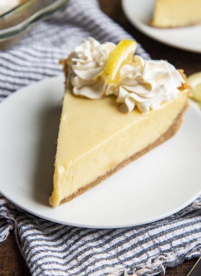 Lemon Cream Pie topped with whipped cream on a white plate