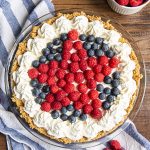 A no bake red white and blueberry cheesecake topped with whipped cream on the edges and star design