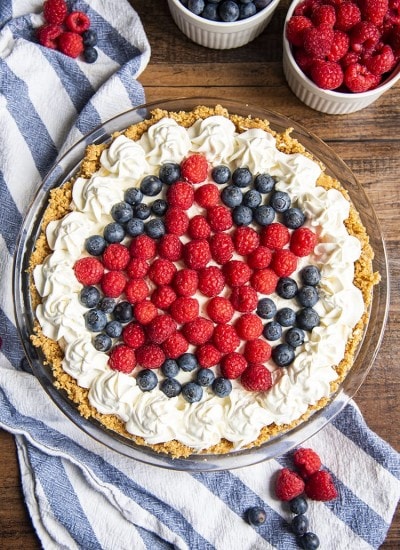 A no bake red white and blueberry cheesecake topped with whipped cream on the edges and star design