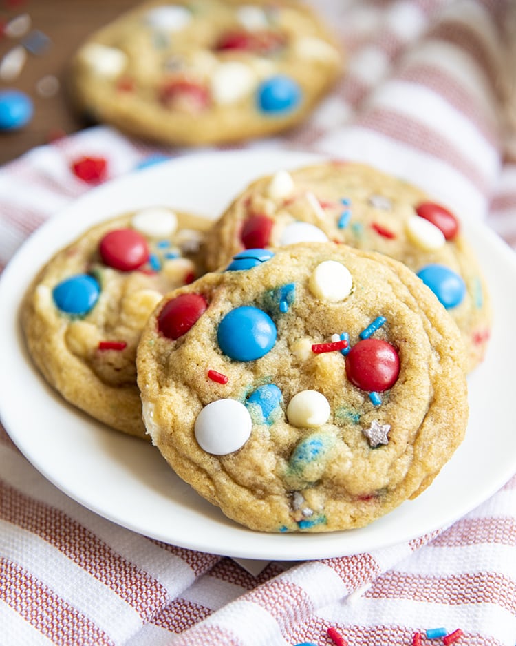 Fourth of July Cookies filled with red white and blue m&ms, white chocolate chips, and sprinkles on a white plate
