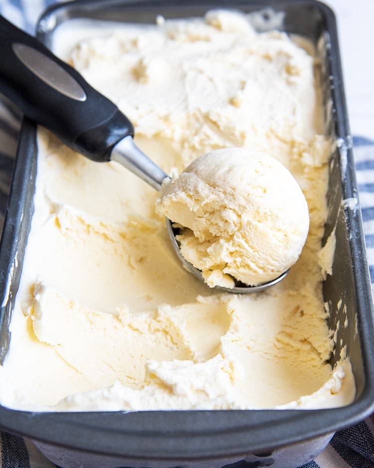 Peach ice cream in a pan, scooped with an ice cream scoop