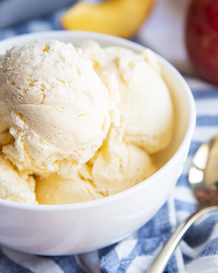 A closeup of peach ice cream in a white bowl.