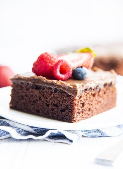 A slice of chocolate sheet cake on a plate, and topped with fresh berries