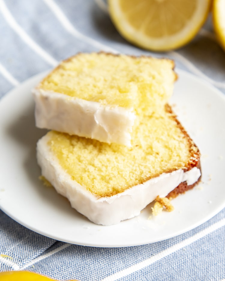 A piece of copycat starbucks lemon loaf broken in half and put on a white plate.