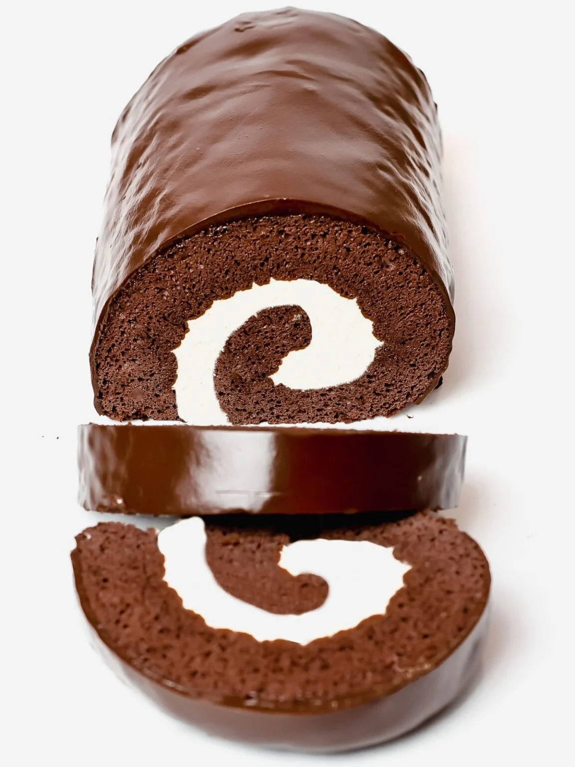 A chocolate swiss roll with two slices cut off the front and laying down.