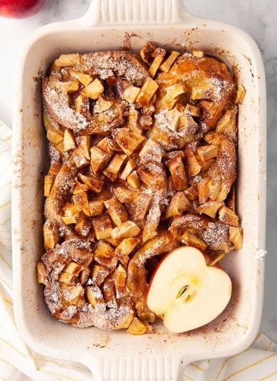 Overnight apple french toast in a pan with a sliced apple