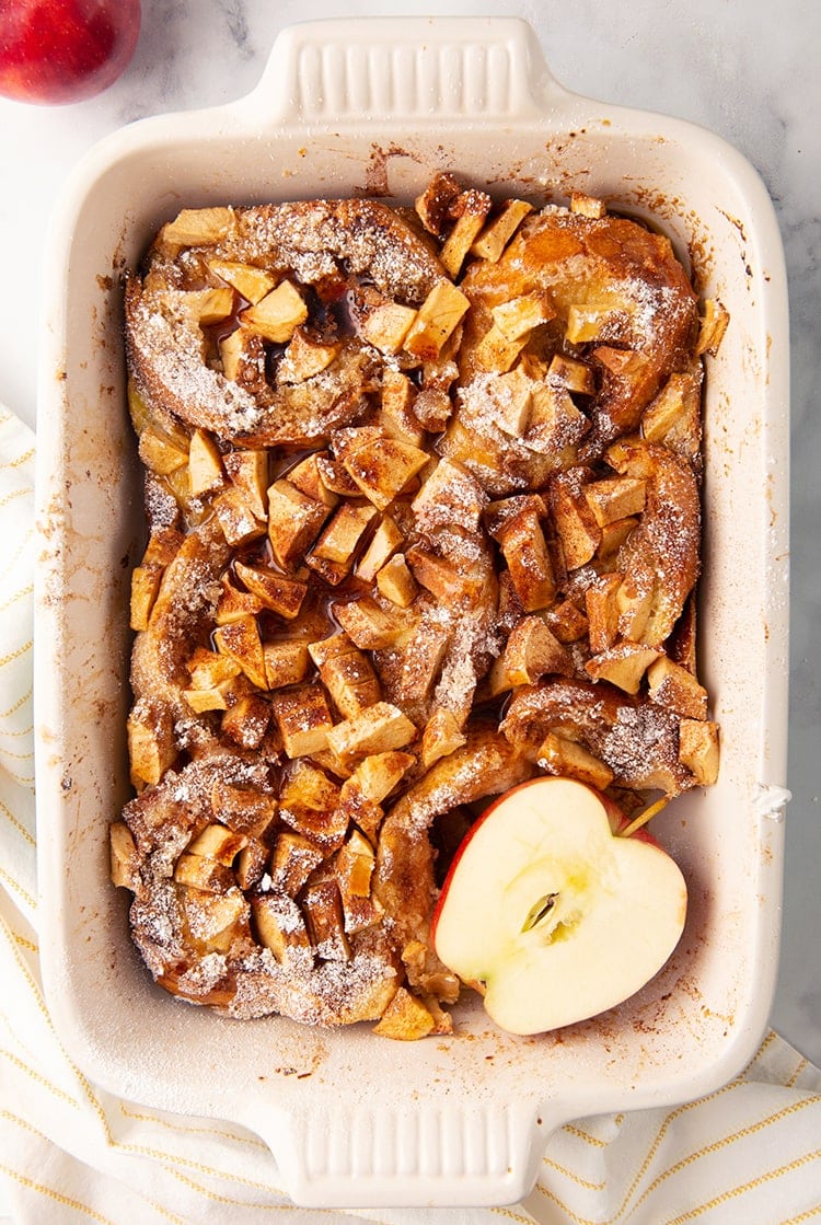 Overnight apple french toast in a pan with a sliced apple
