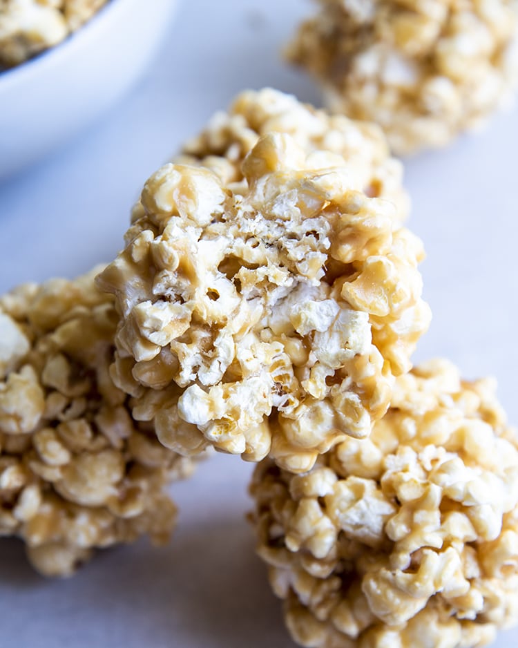 A caramel popcorn ball with a bite taken out of it.