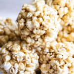 A stack of caramel popcorn balls in a white bowl.