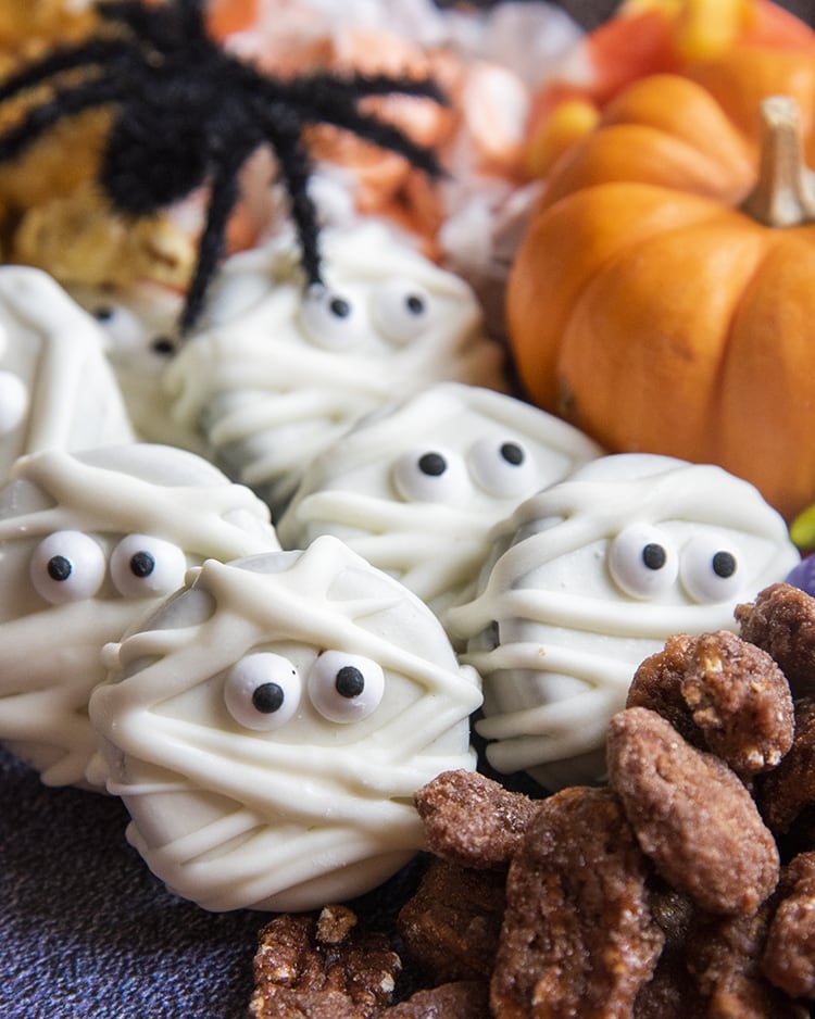 A close-up of a halloween charcuterie board with mummy oreos and other halloween candies.