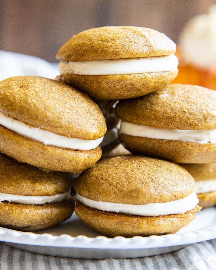 A stack of pumpkin whoopie pies on a plate.