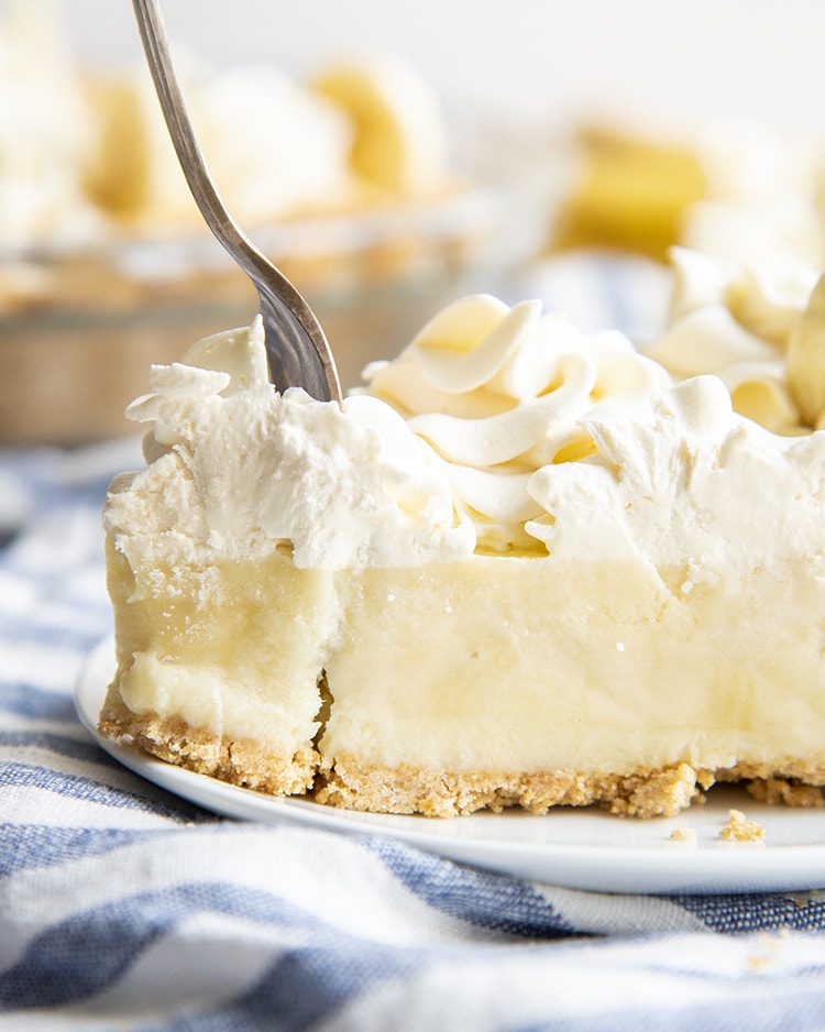 A fork separating a bite of banana cream pie.