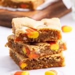 A stack of three pieces of peanut butter blondies full of candy corn pieces.