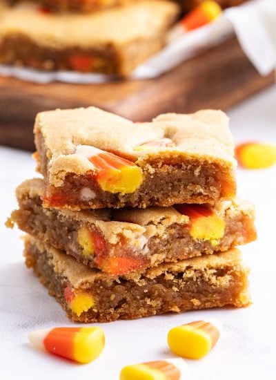 A stack of three pieces of peanut butter blondies full of candy corn pieces.