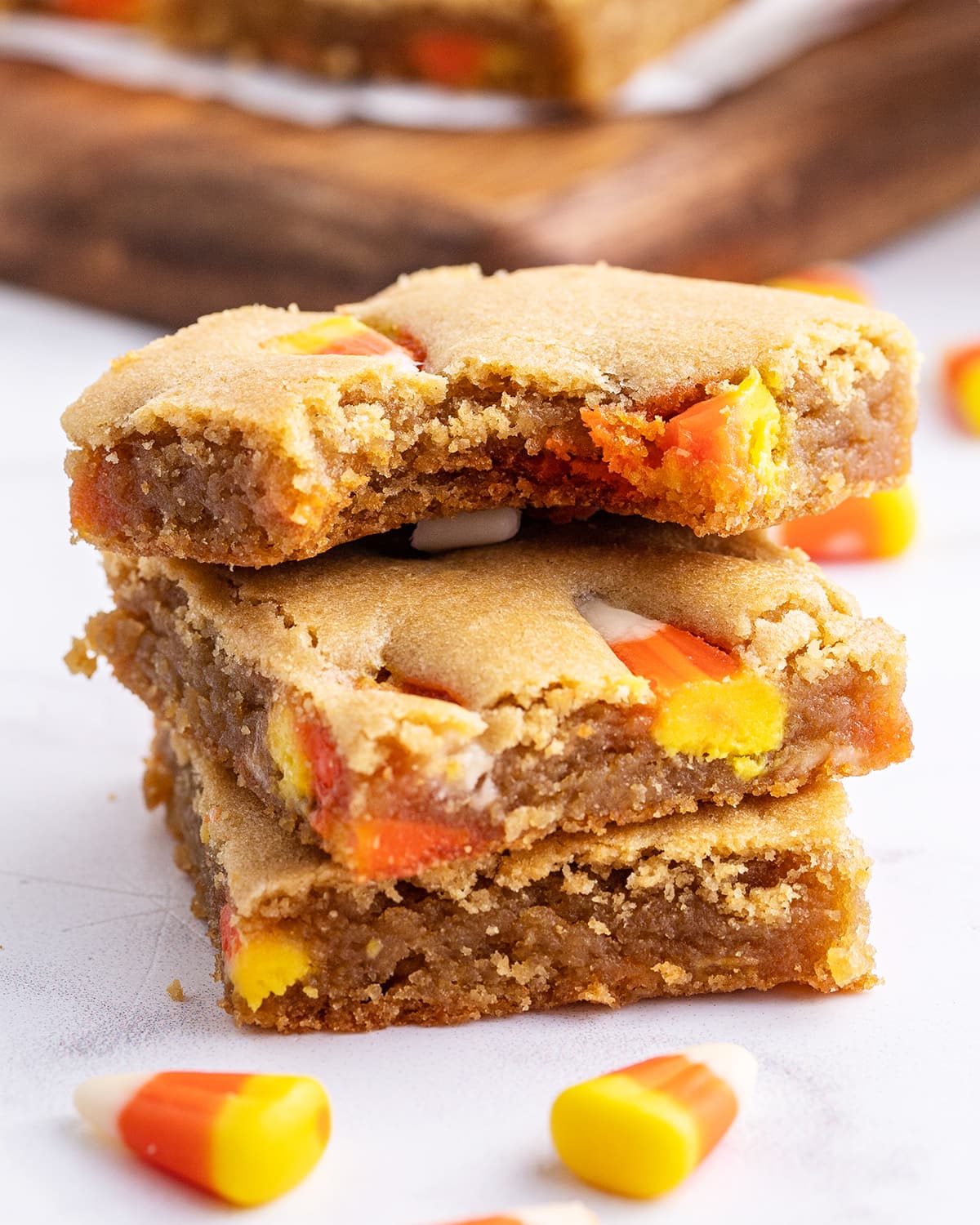 A stack of candy corn peanut butter bar pieces with a bite out of the top piece. 