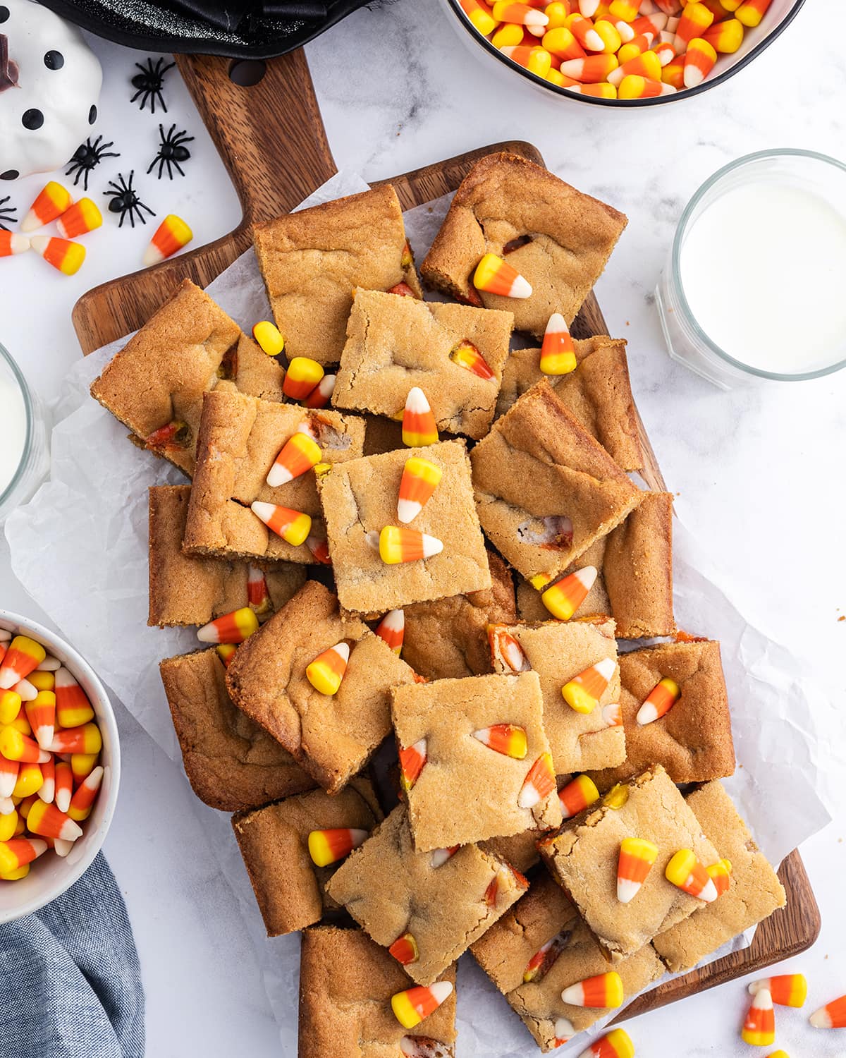 A wooden board topped with pieces of peanut butter blondie topped with candy corn.