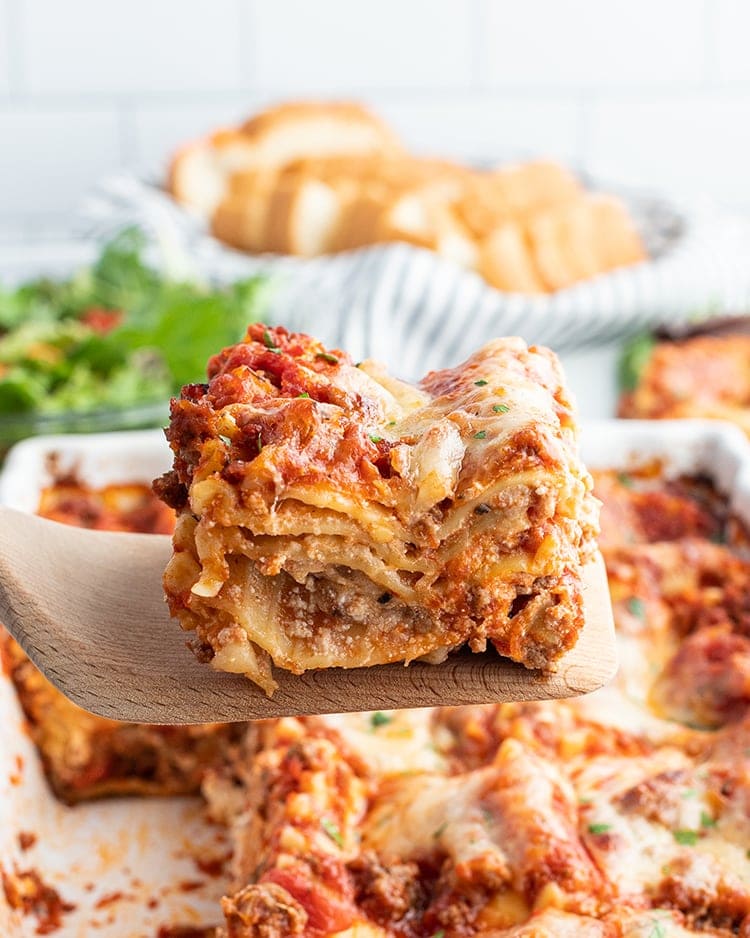 A piece of lasagna on a spatula being lifted out of the pan.