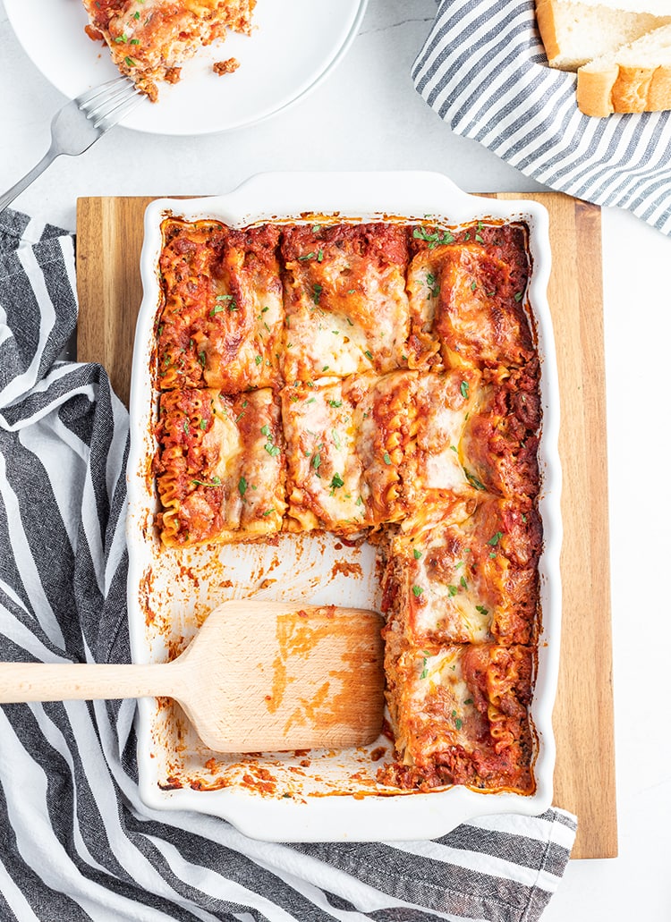 Above shot of classic lasagna in a pan with parsley and melted cheese on top with a spatula.