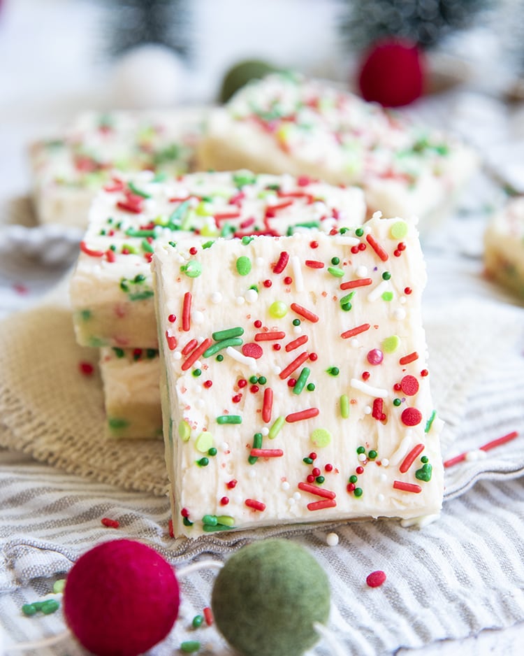 A sugar cookie bar topped with white frosting and Christmas sprinkles.