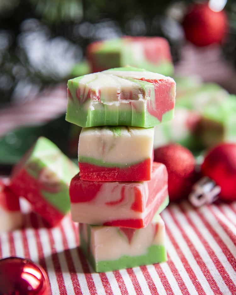 A stack of Christmas swirled fudge, with 4 pieces in the stack. The top piece has a bite taken out of it.