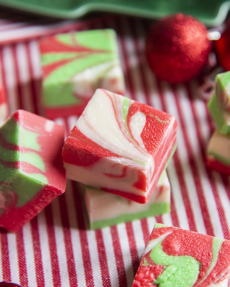 Christmas swirled fudge, on a red and white cloth. The fudge has red, white and green colors swirled throughout.