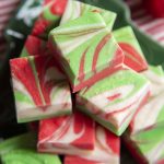 A pile of white chocolate microwave fudge, that is swirled with red and green colors throughout.
