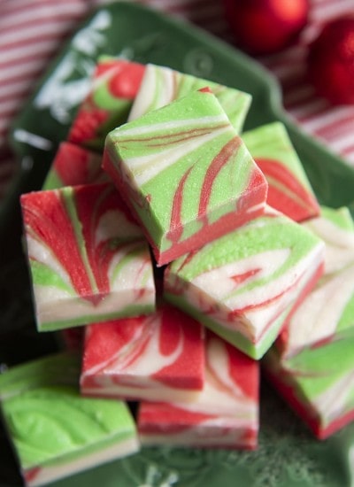 A pile of white chocolate microwave fudge, that is swirled with red and green colors throughout.