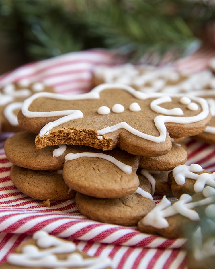 Gingerbread men stacked in a pile. The top cookie has a bite taken out of it's leg.