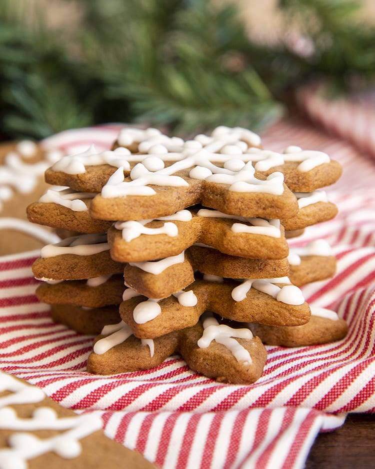 A stack of snowflake shaped gingerbread cookies on a red and white pinstripe cloth.