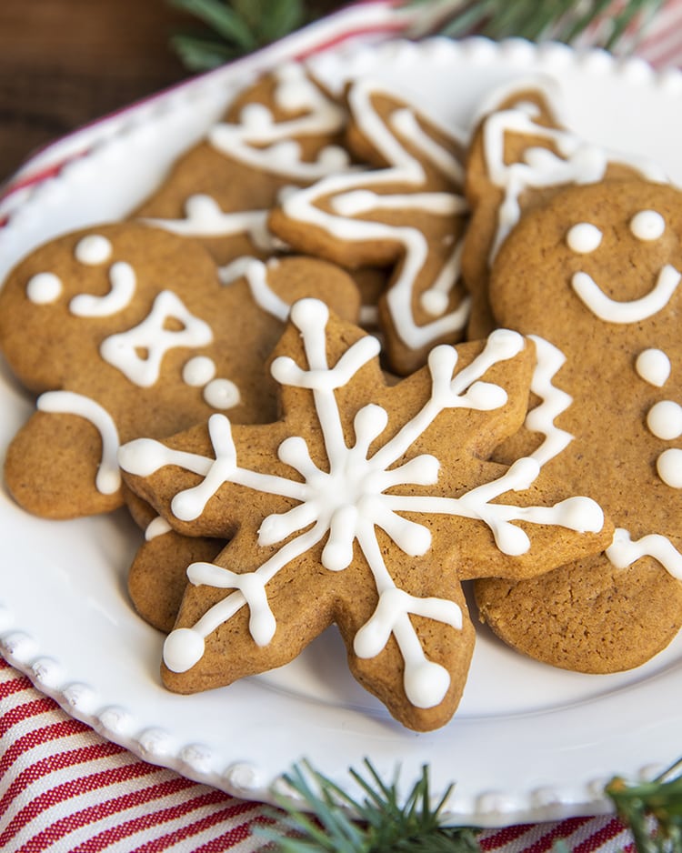 A plate of gingerbread cookies. The front cookie is a snowflake.