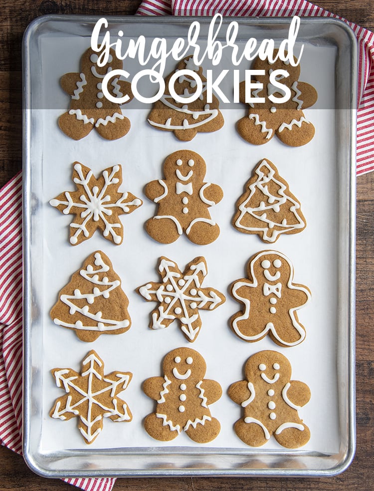 A cookie sheet lined with gingerbread cookies. There are gingerbread men, trees, and snowflakes, decorated with a simple royal icing.