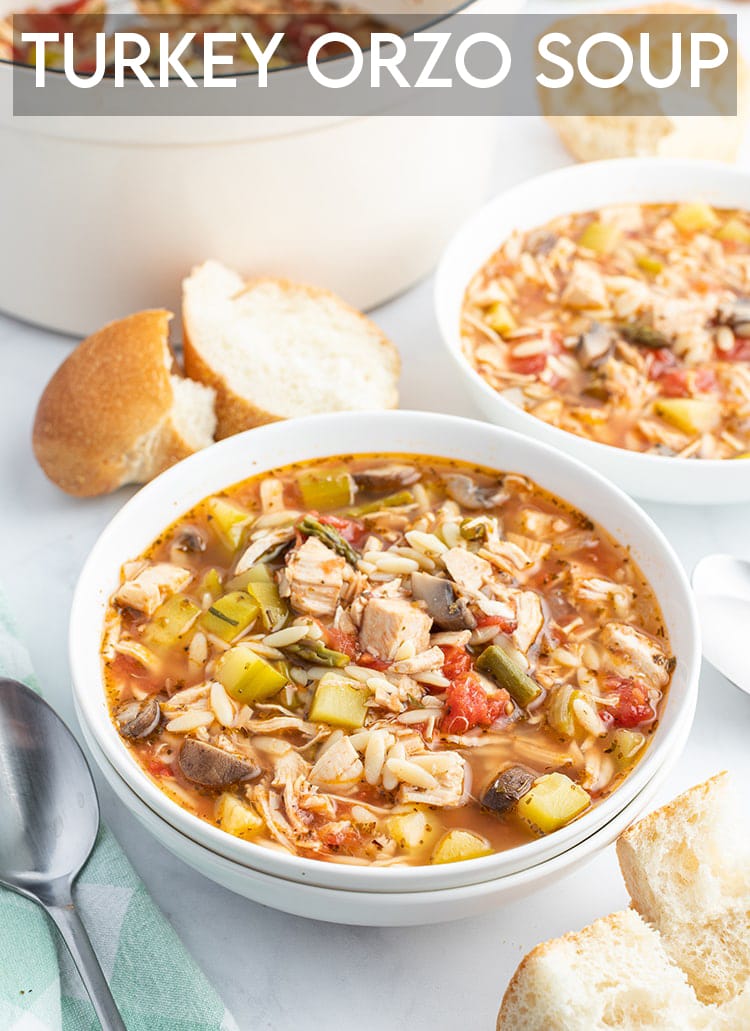 A bowl of turkey and orzo soup with french bread on the side with a text overlay for pinterest.