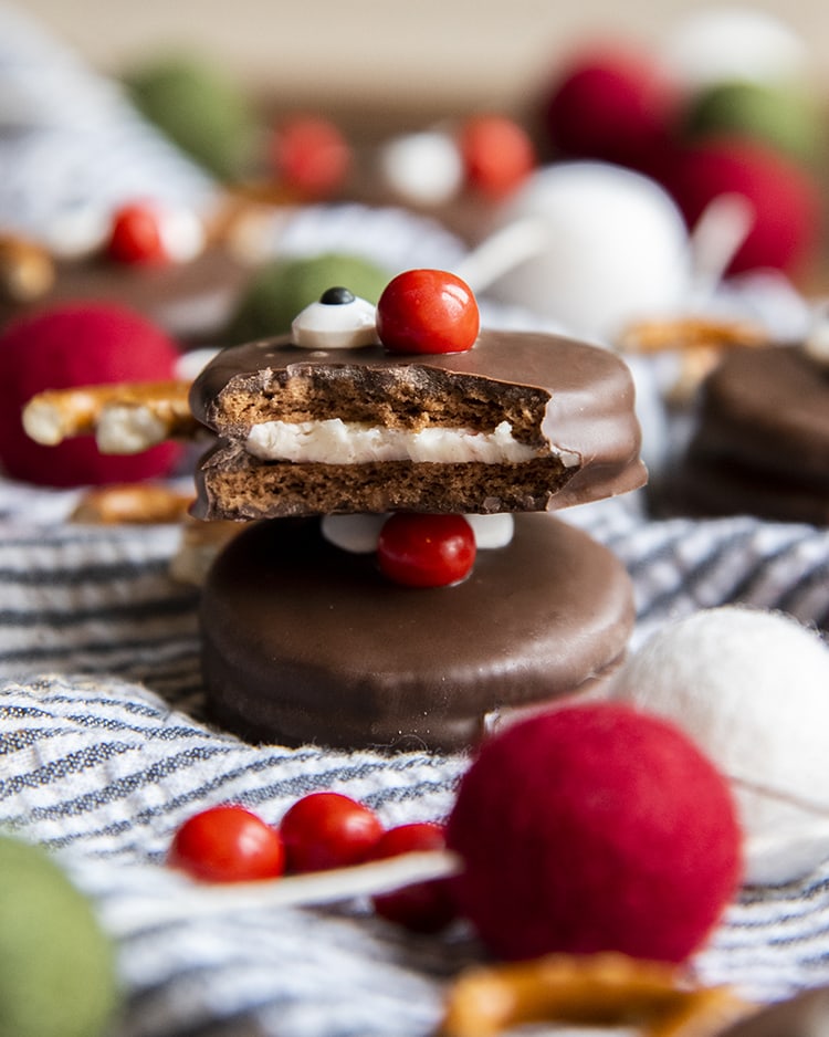 Two Oreo Reindeer stacked. The top one has a bite out of it, and you can see one eye and the red chocolate nose on top.