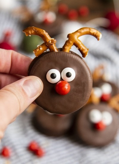 An Oreo dipped in chocolate and decorated with candy eyes and pretzels to look like a reindeer.