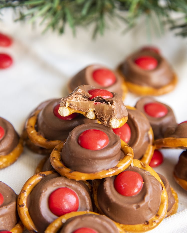 Rolo pretzel treats with a red m&m on top to look like Rudolph's nose. One is bitten into to show the chewy caramel in the middle.