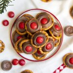 A small plate full of "rudolph noses" treats. Which are round pretzels topped with a slightly melted rolo, and a red m&m on top.