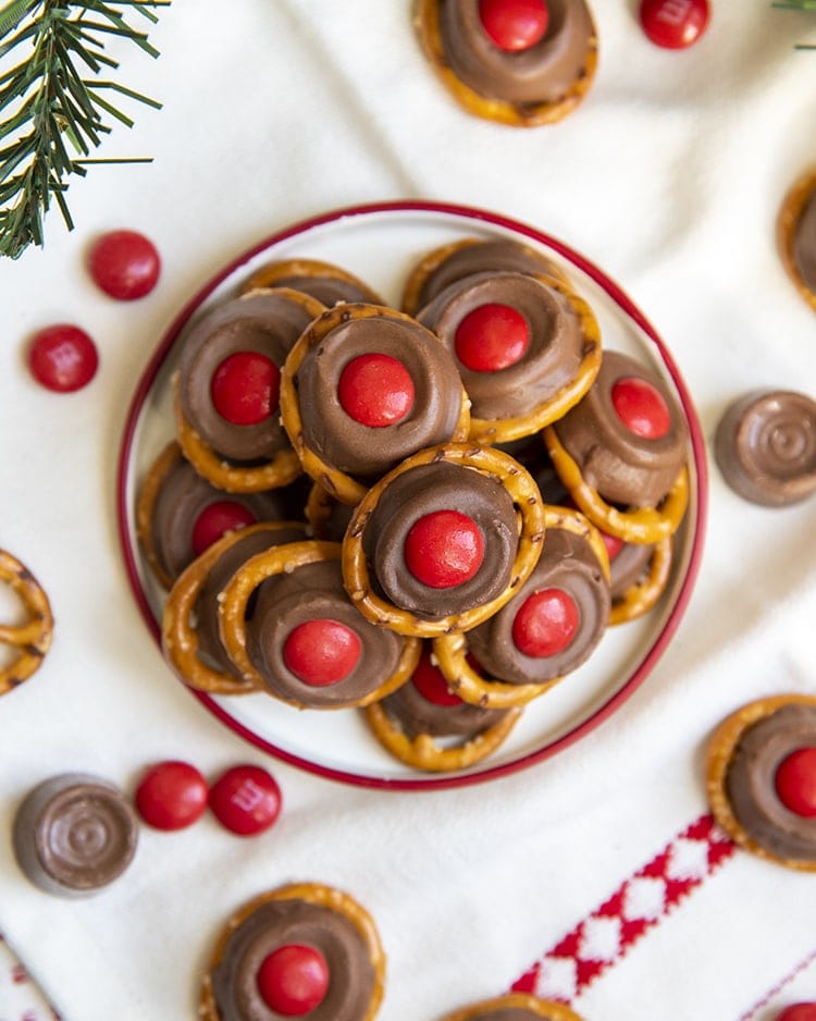 A small plate full of "rudolph noses" treats. Which are round pretzels topped with a slightly melted rolo, and a red m&m on top.