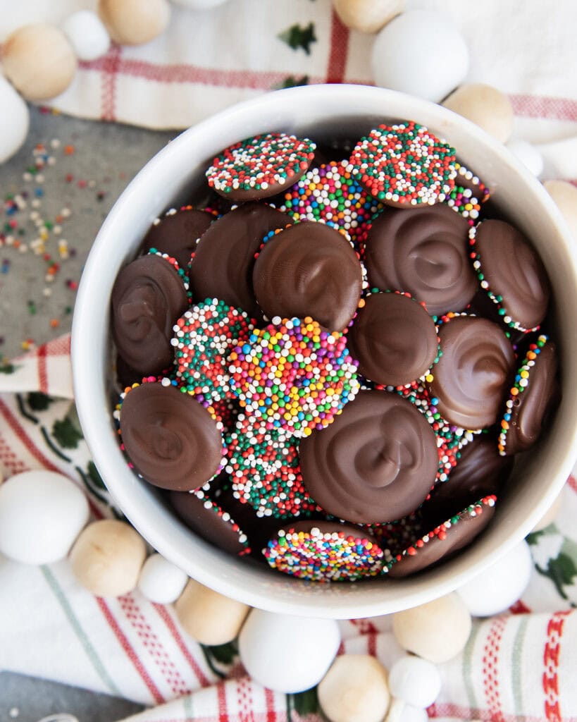 A bowl of chocolate non pareils, some have the chocolate side facing up, some the sprinkle side. 