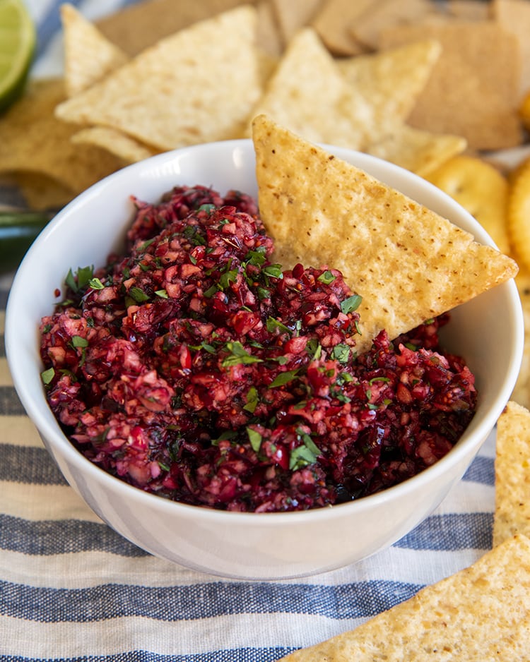 A bowl of cranberry salsa with a tortilla chip in the bowl.