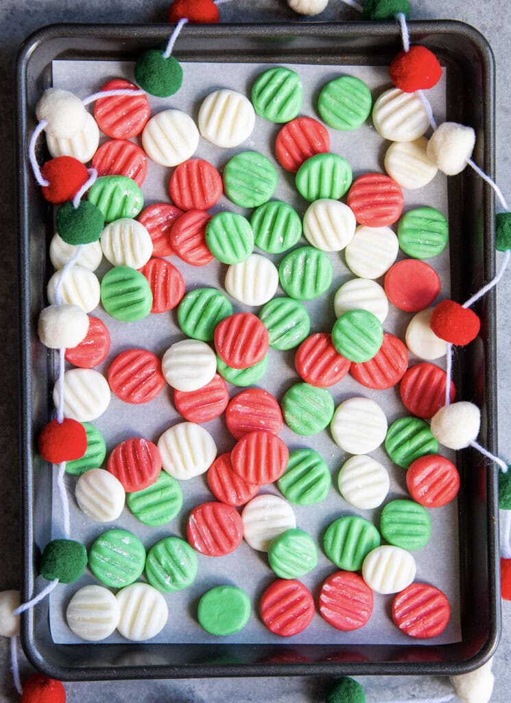 An above view of red, white, and green cream cheese mints on a cookie sheet.