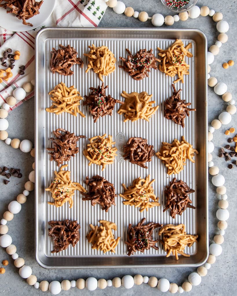 A cookie sheet of both chocolate and butterscotch haystack cookies topped with sprinkles.