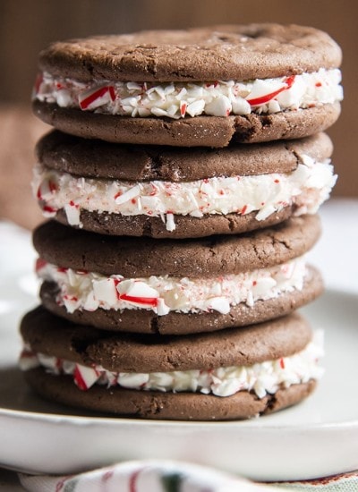 A stack of homemade cake mix oreo cookies with peppermint candy cane pieces stuck to the frosting in the middle.