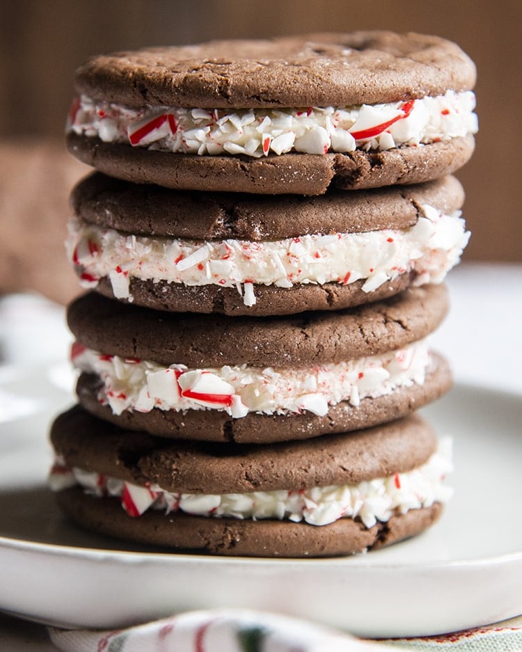 A stack of homemade cake mix oreo cookies with peppermint candy cane pieces stuck to the frosting in the middle.