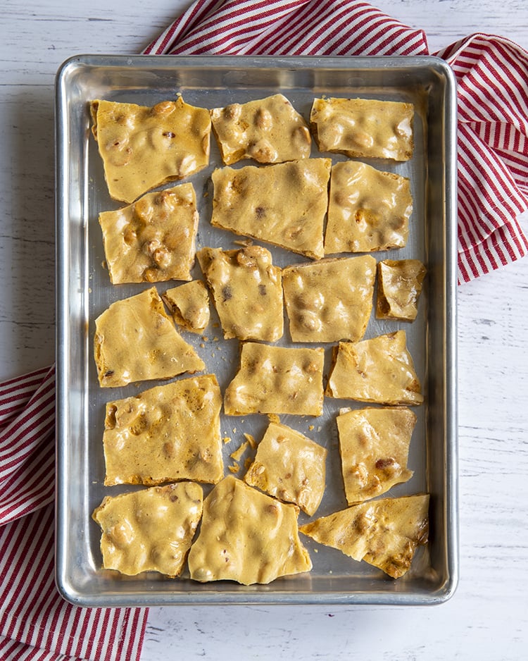 A cookie sheet covered in broken pieces of peanut brittle.