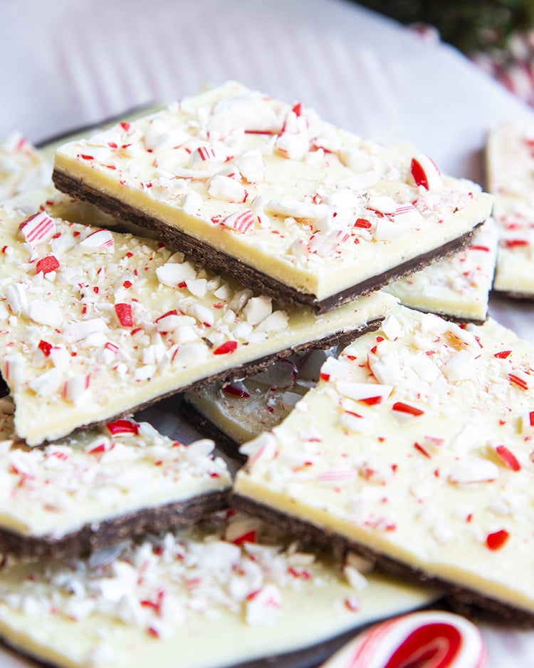 A pile of pieces of peppermint bark on parchment paper. You can see the layers of dark chocolate, white chocolate, and peppermint pieces.
