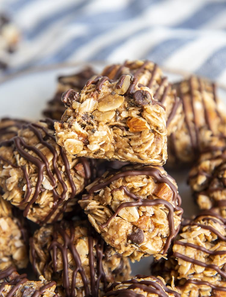 A pile of almond joy energy bites, and the top bite is bitten into showing the oats, and pieces of almonds in the middle.