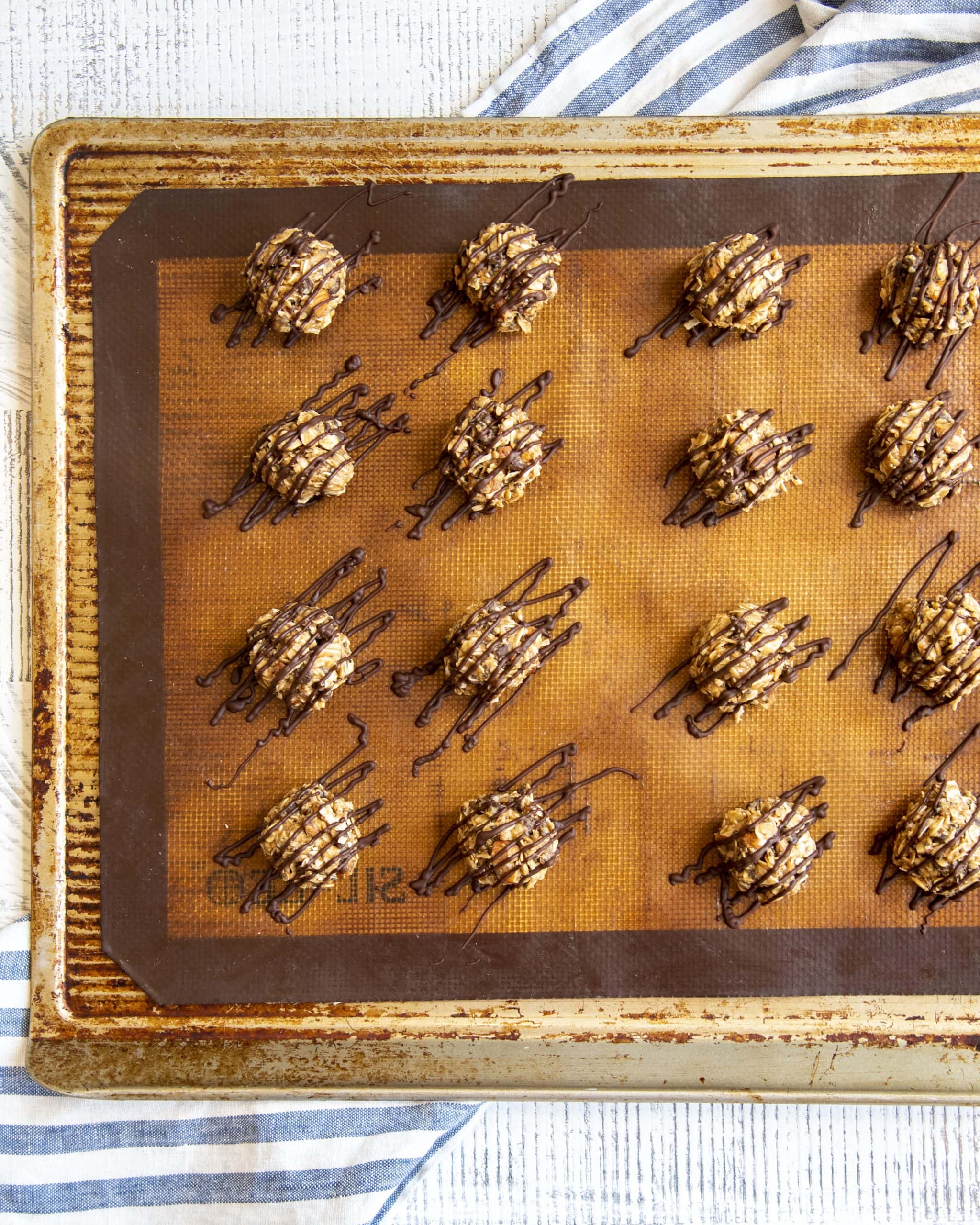 Almond joy energy bites on a baking pan, showing chocolate drizzled on the tops, and over drizzled on the sides.