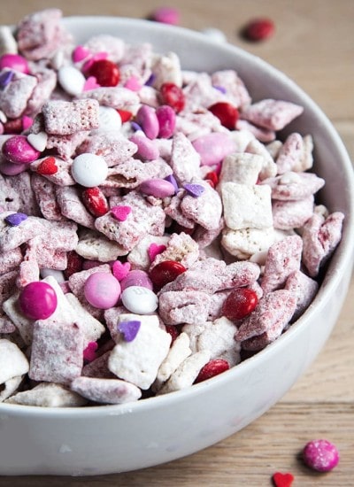 A bowl of pink and white puppy chow full of valentine m&ms and sprinkles