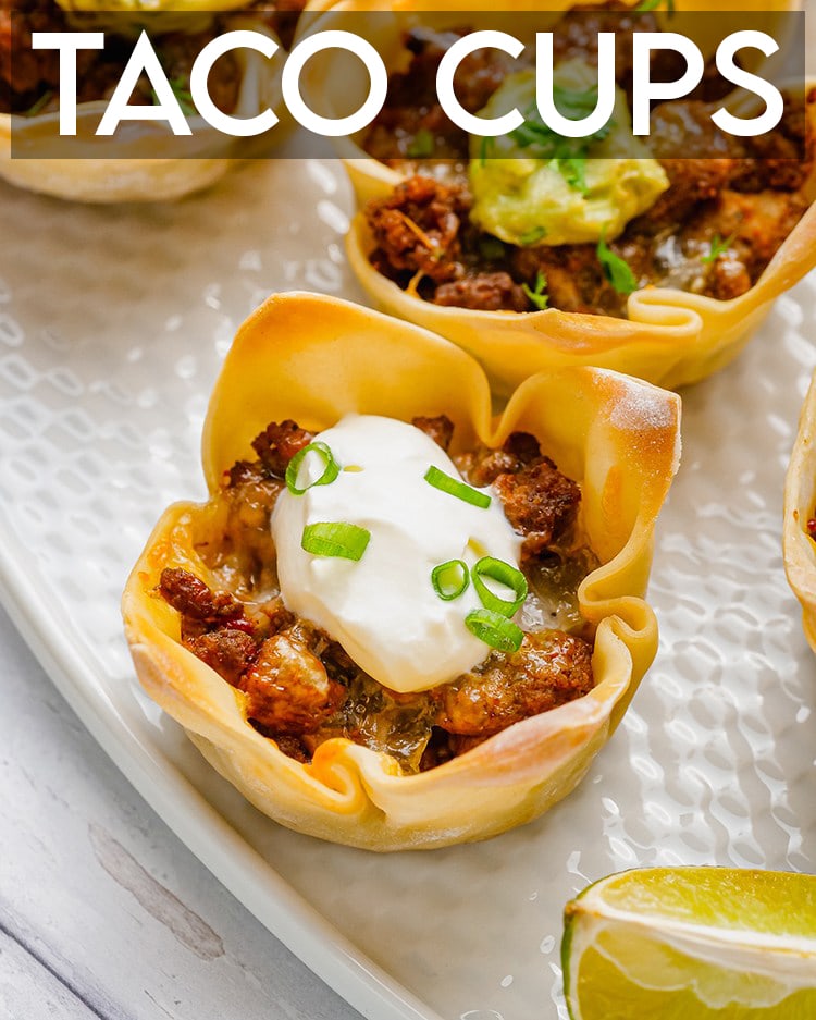 Close up photo of wonton taco cups with sour cream on top on a white plate.